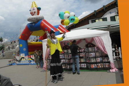 Stelzen - Clown verteilt Luftballons
